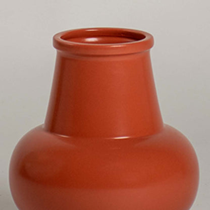 Closeup view of the orange ceramic vase showing its smooth glossy finish and modern rounded silhouette for stylish home decor.