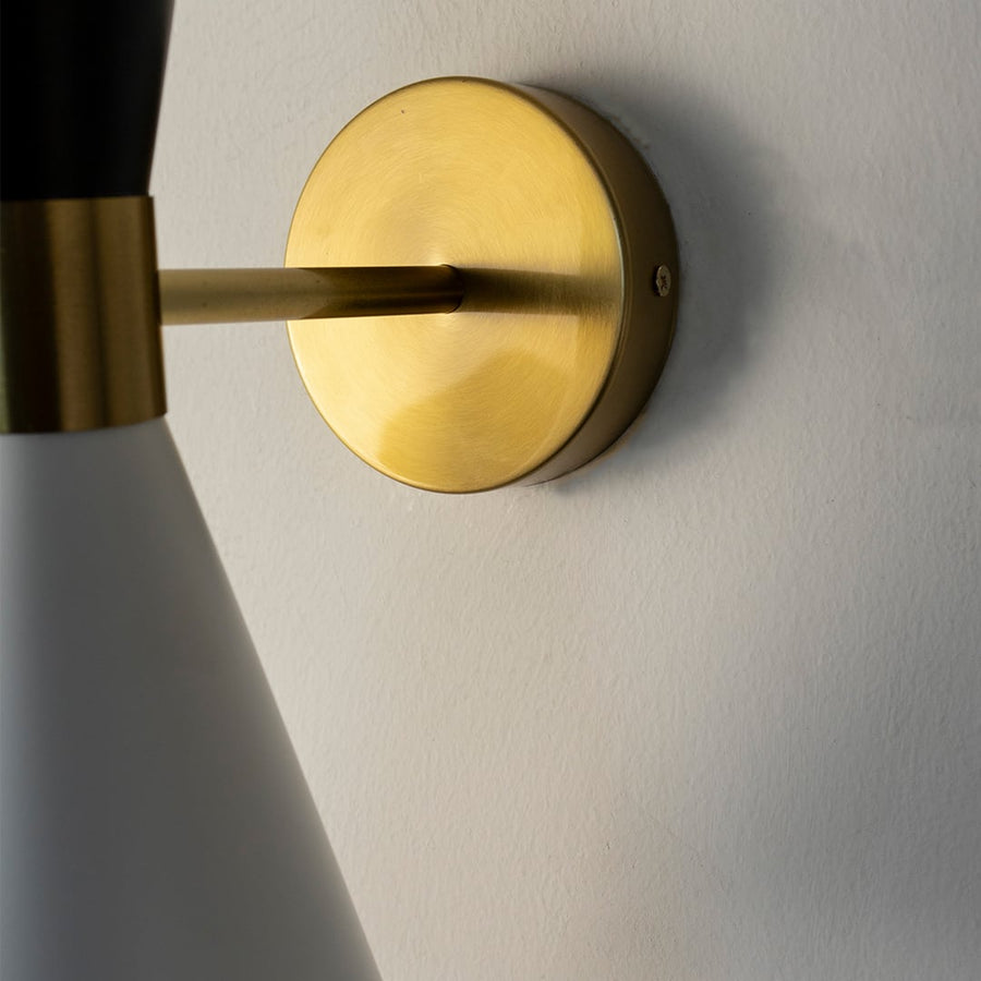 Closeup of dual tone wall light showing matte black and white metal shades with gold accent for stylish interiors.