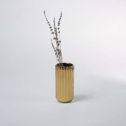 A shiny gold vase with a ribbed texture displayed in a soft minimal setting creating a warm elegant lifestyle look that highlights its modern charm.