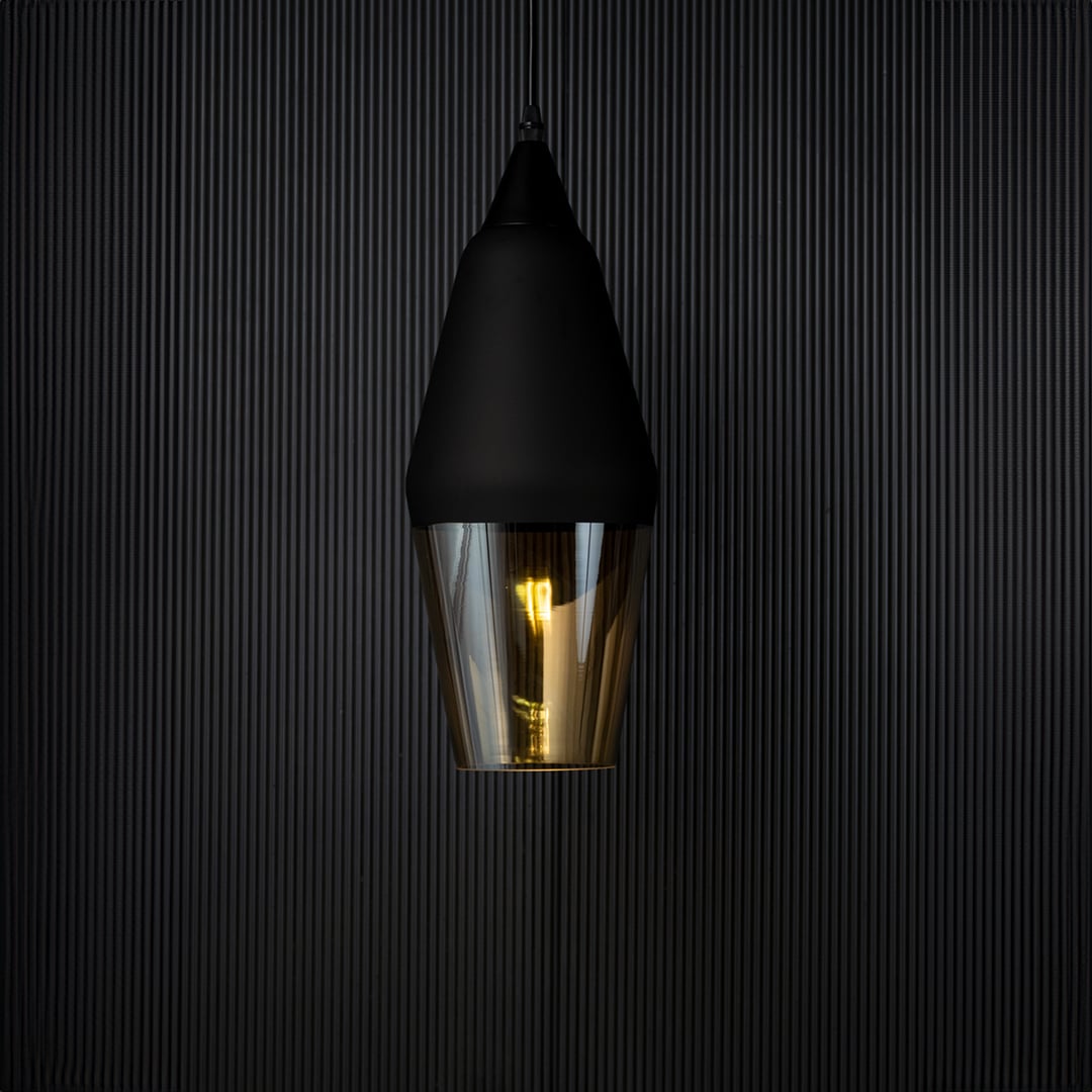 Pendant light turned on against a black background with warm illumination glowing through the amber glass shade emphasizing the elegant contrast and modern style.
