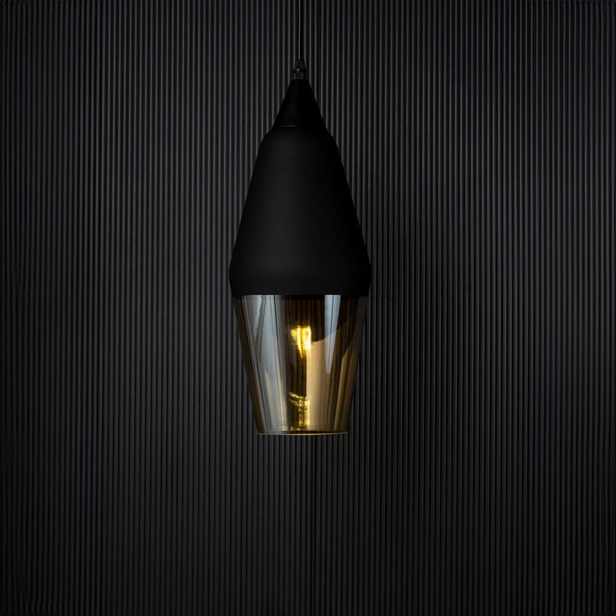 Pendant light turned on against a black background with warm illumination glowing through the amber glass shade emphasizing the elegant contrast and modern style.