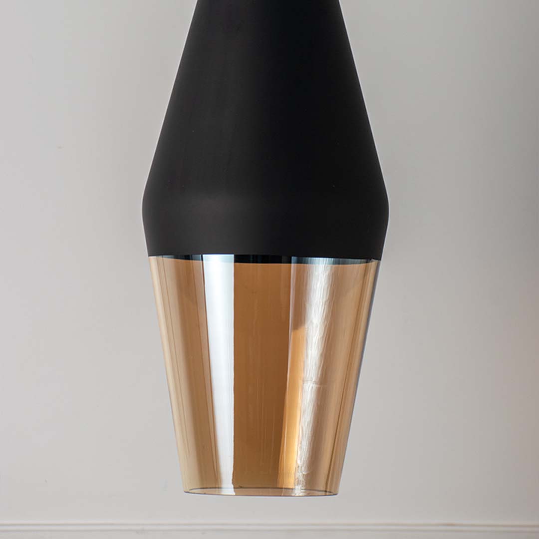 Closeup of black metal pendant light with amber glass diffuser showcasing premium craftsmanship and elegance.