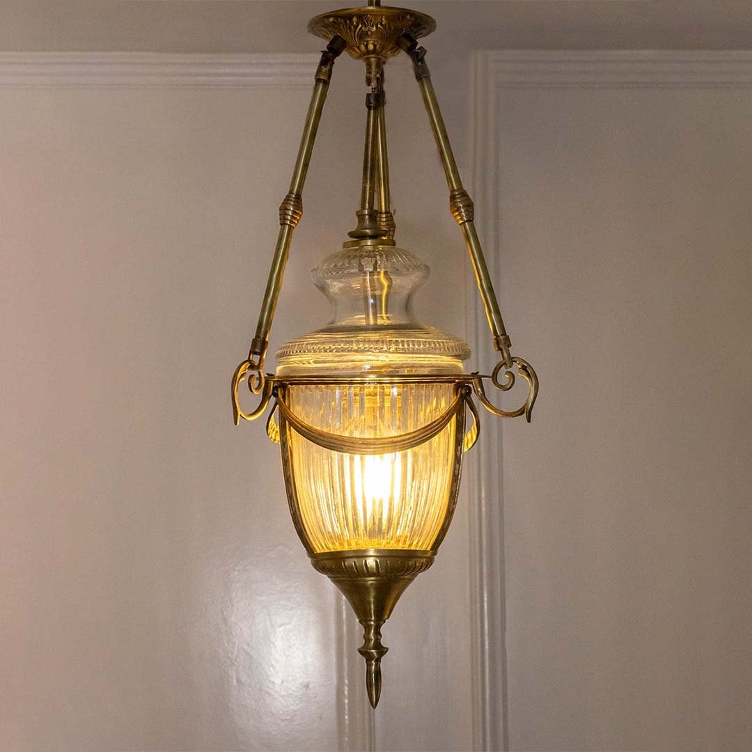 Antique brass and clear glass lantern pendant light adding timeless elegance to grand spaces.