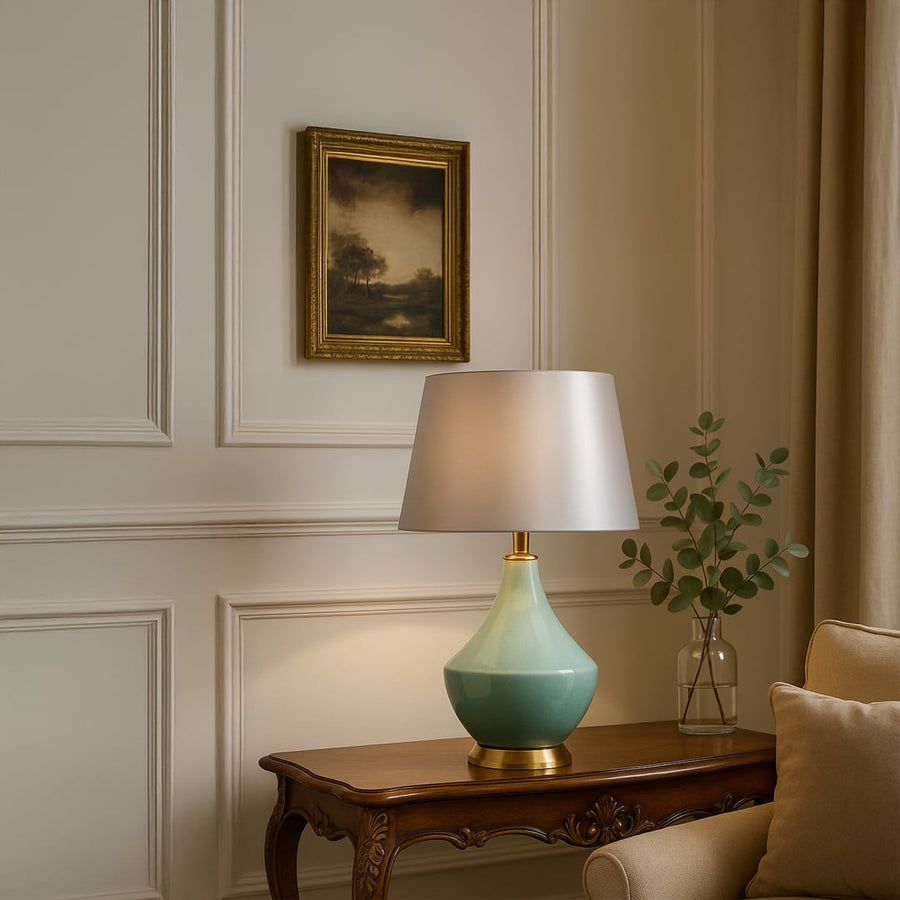 Modern green ceramic table lamp styled in living room decor with framed paintings offering a warm and sophisticated glow.