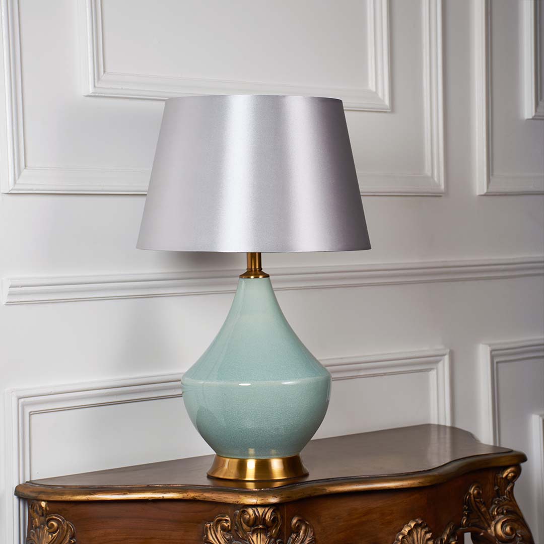 Elegant green table lamp with gold base and beige shade displayed on white background with light off showcasing natural ceramic beauty.