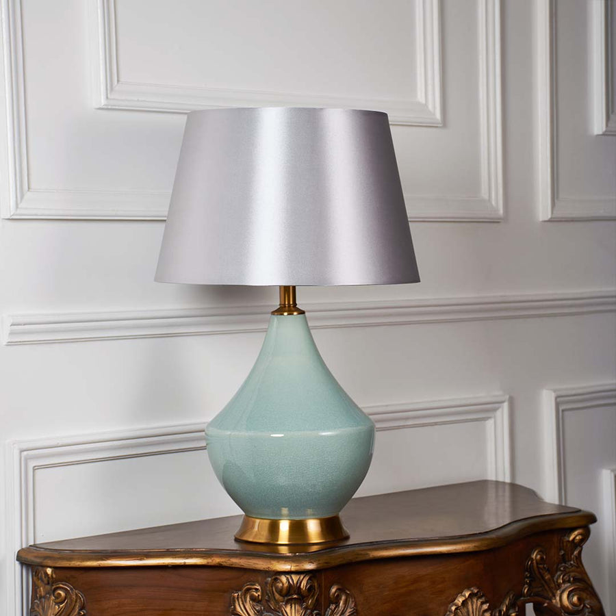 Elegant green table lamp with gold base and beige shade displayed on white background with light off showcasing natural ceramic beauty.