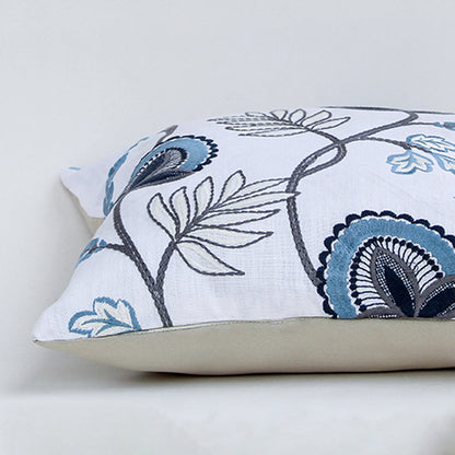 Soft cotton cushion cover with blue floral embroidery shown at an angle adding a fresh nature inspired décor element with a breathable smooth and skin friendly fabric suitable for modern interiors.