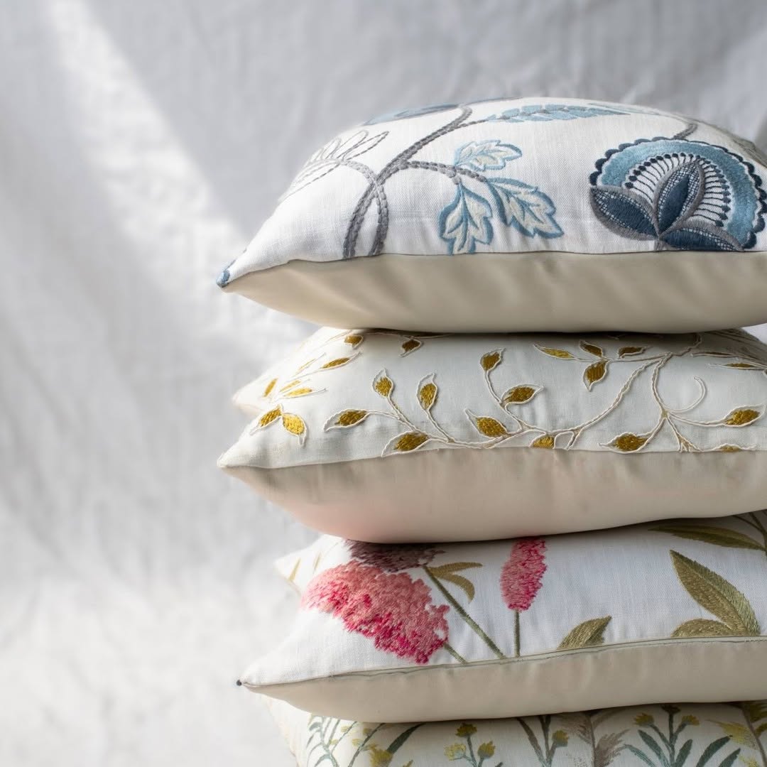 Soft cotton cushion covers in assorted floral embroidery designs stacked together offering a warm nature inspired décor look with breathable gentle and skin friendly fabric quality.