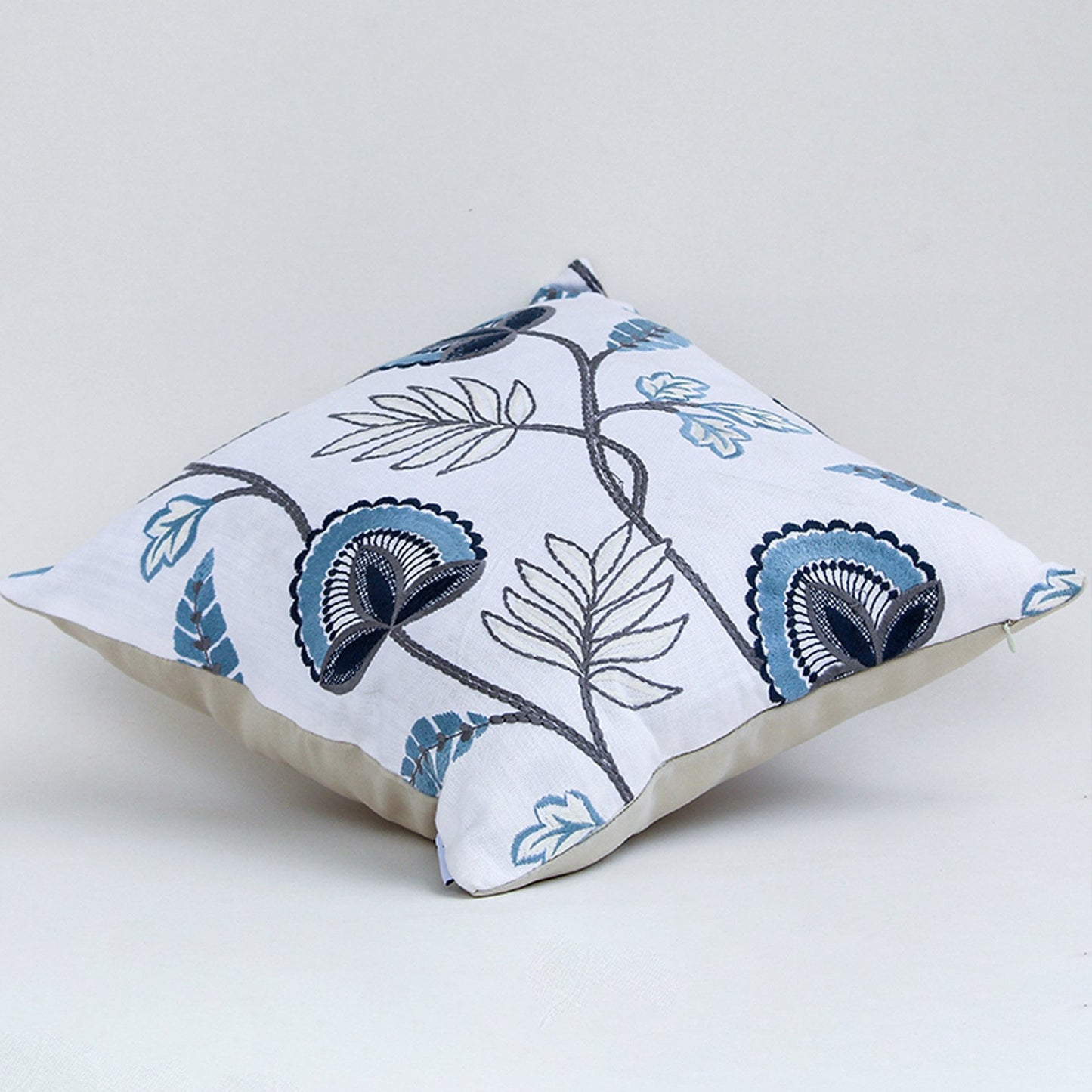 Soft cotton cushion cover with blue floral embroidery shown at an angle creating a cool nature inspired décor accent with a breathable smooth and skin friendly fabric finish for modern styling.