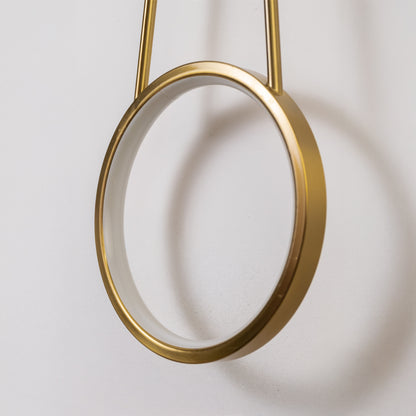 Closeup wall light in gold metal finish with circular ring design for bedroom or living decor lighting white background.