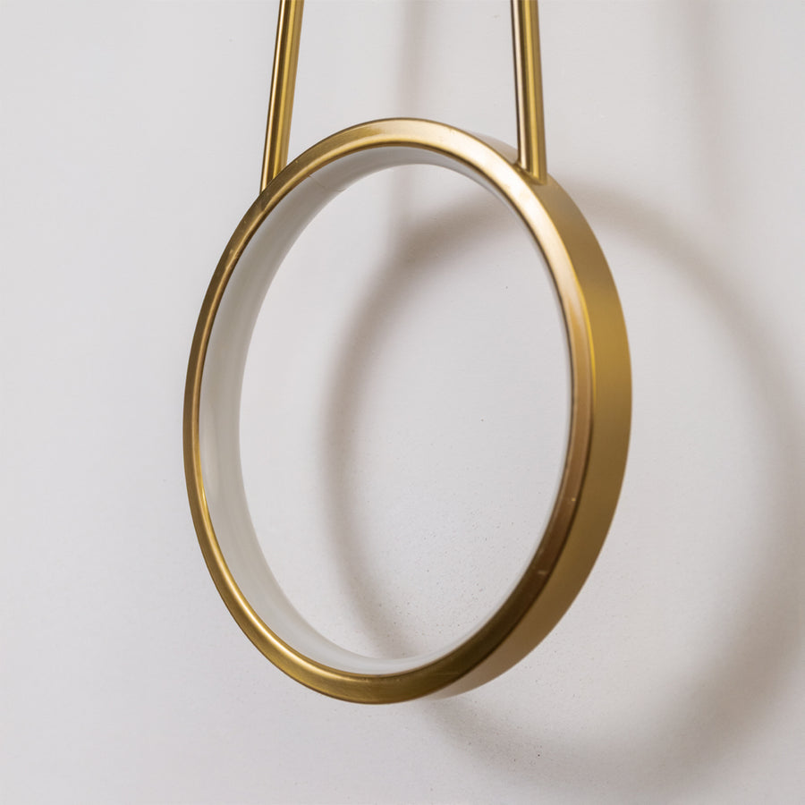 Closeup wall light in gold metal finish with circular ring design for bedroom or living decor lighting white background.