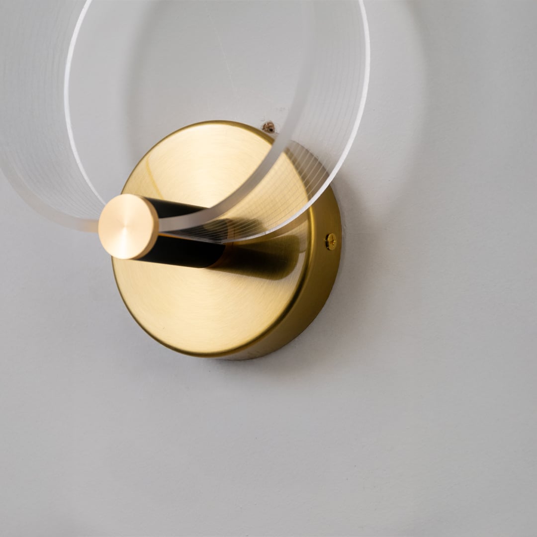 Closeup of gold metal wall light with frosted acrylic ring showing refined finish and premium modern design details.