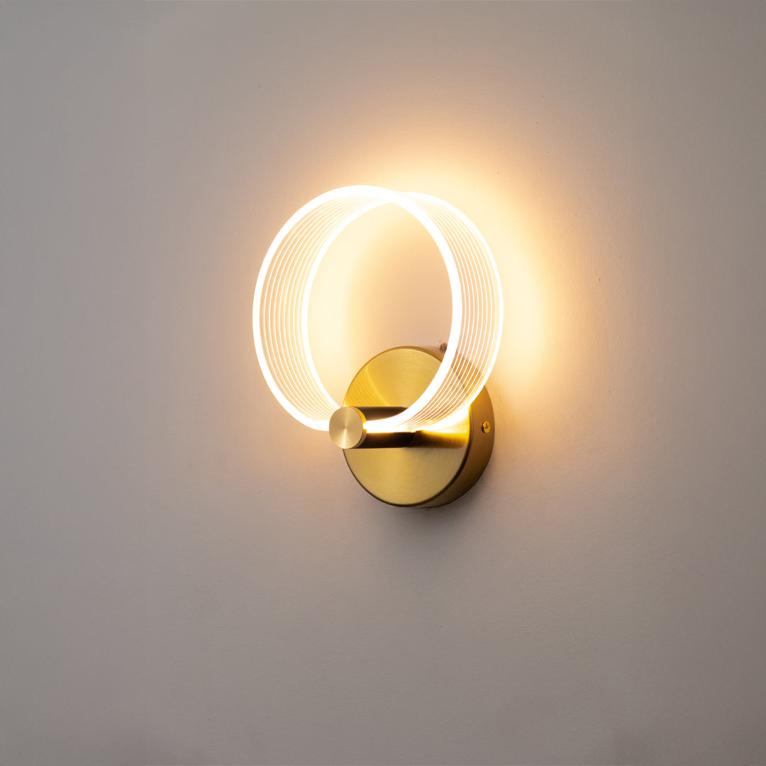 Modern wall light in gold metal finish with ring LED design for bedroom or living decor lighting placement white background.
