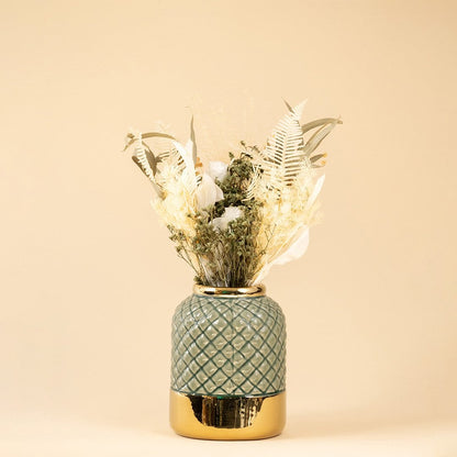 Blue ceramic vase with raised diamond pattern and metallic gold base viewed  against a neutral backdrop.