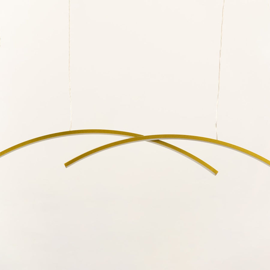 A gold curved ceiling light with intersecting arcs perfect for modern LED lighting and minimal chandelier décor enhancing elegant contemporary home spaces.