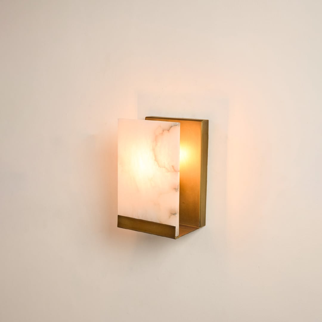 Rectangular metal wall sconce illuminated on white background featuring alabaster texture and warm glow perfect for refined and elegant interiors.