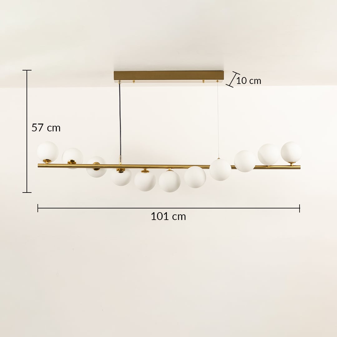 Gold linear ceiling chandelier with globe bulbs measuring 103 cm width and 57 cm height against a white wall background with lights on ideal for modern designer lighting décor.