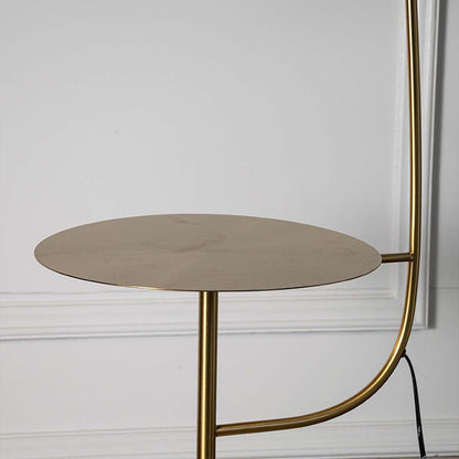 Closeup of gold floor lamp with cylindrical shade and side table showing sleek metallic finish.