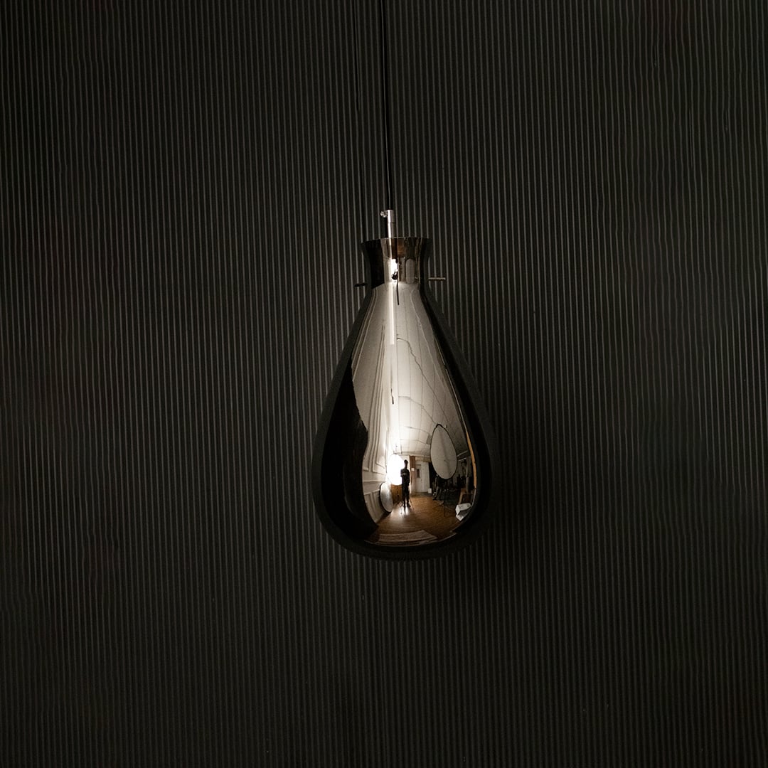 Smoked glass pendant light displayed on dark background with lights off emphasizing smooth teardrop design and glossy finish.
