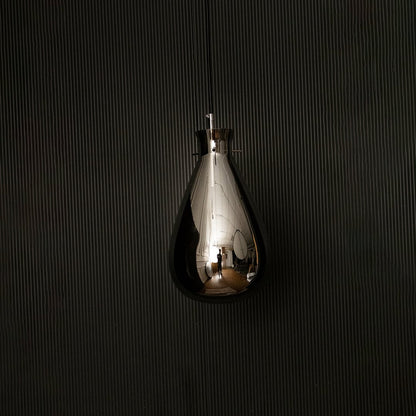 Smoked glass pendant light displayed on dark background with lights off emphasizing smooth teardrop design and glossy finish.