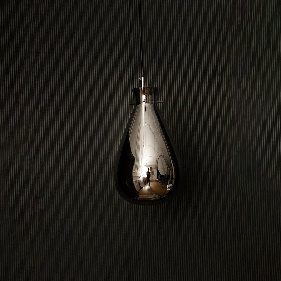 Smoked glass pendant light displayed on dark background with lights off emphasizing smooth teardrop design and glossy finish.