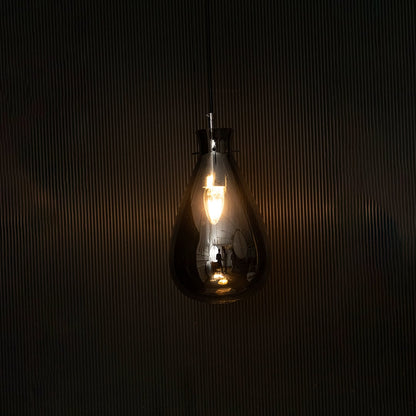 Elegant smoked chrome glass pendant light illuminated beautifully on dark background highlighting its artistic shape and glossy finish.