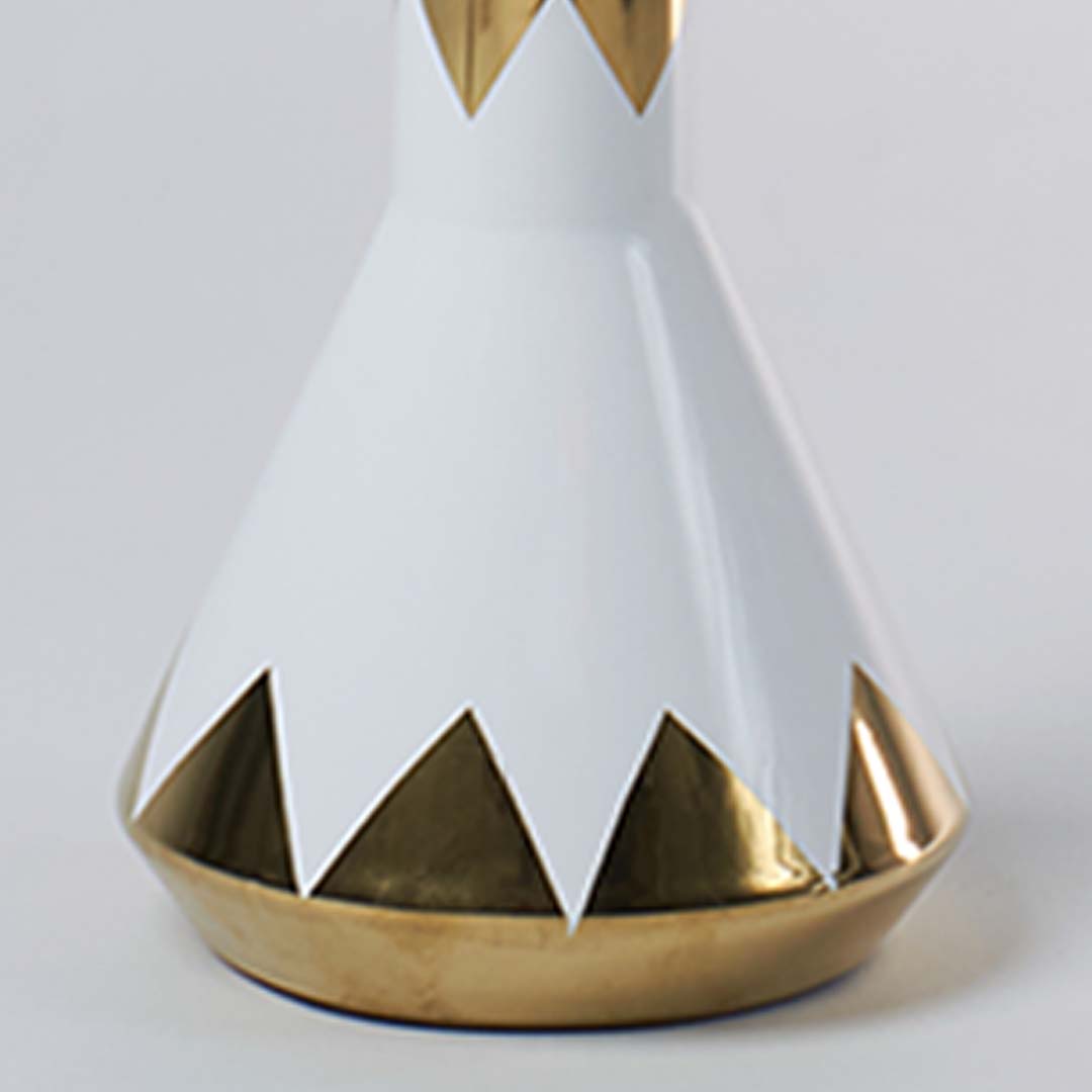 Closeup of white ceramic decor object with gold geometric edging highlighting smooth glaze premium finish and modern decorative detailing.