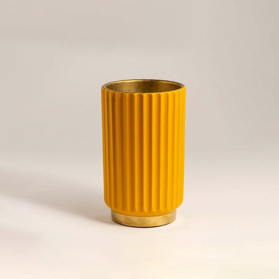 Bright yellow metal vase with ribbed texture and shiny gold base illuminated against a white background for a contemporary look.