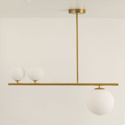 Gold linear chandelier displayed with lights off showing sleek frame frosted glass globes and modern minimalistic aesthetic design.