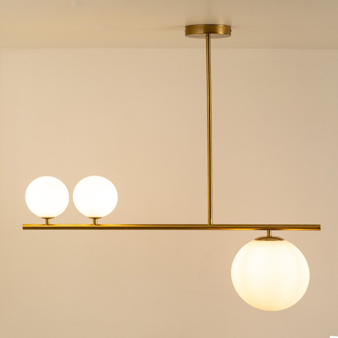 Elegant gold chandelier with glowing frosted glass spheres on white background showcasing contemporary style and refined craftsmanship.