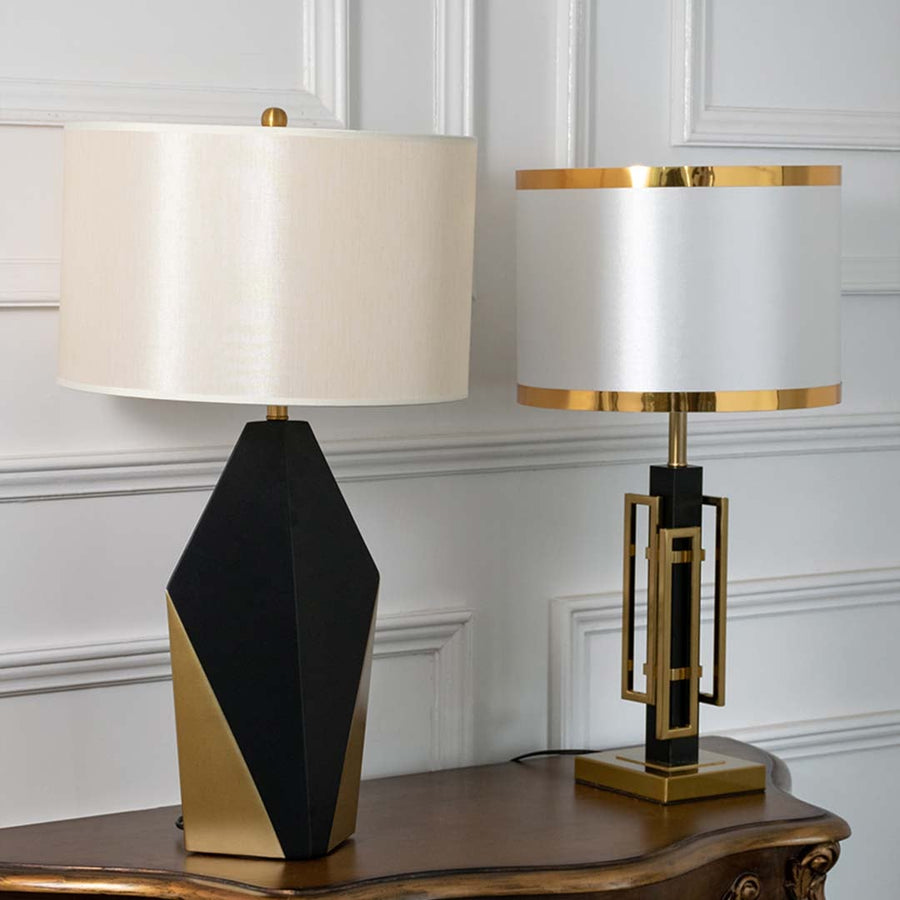 Black and gold geometric table lamps with white drum shades shown together with lights off highlighting striking faceted bases for modern home decor.