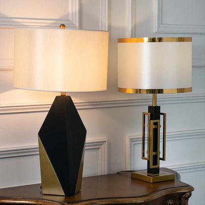 Black and gold geometric table lamps with illuminated white drum shades displayed together showcasing warm contemporary lighting options.