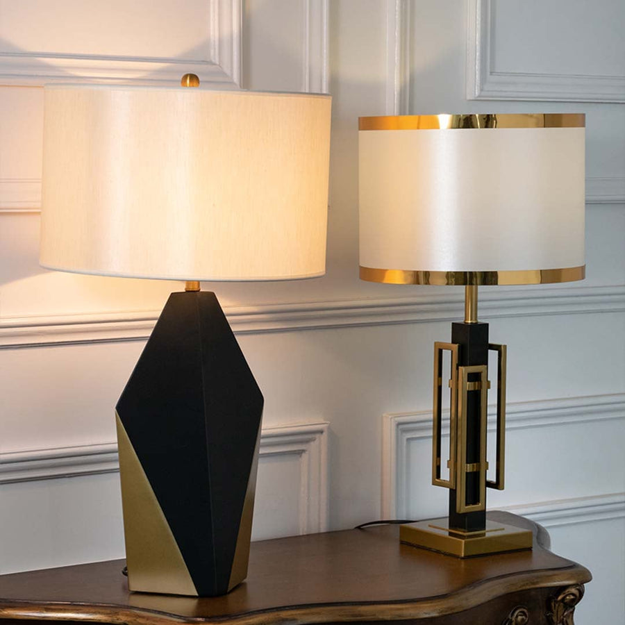 Black and gold geometric table lamps with illuminated white drum shades displayed together showcasing warm contemporary lighting options.