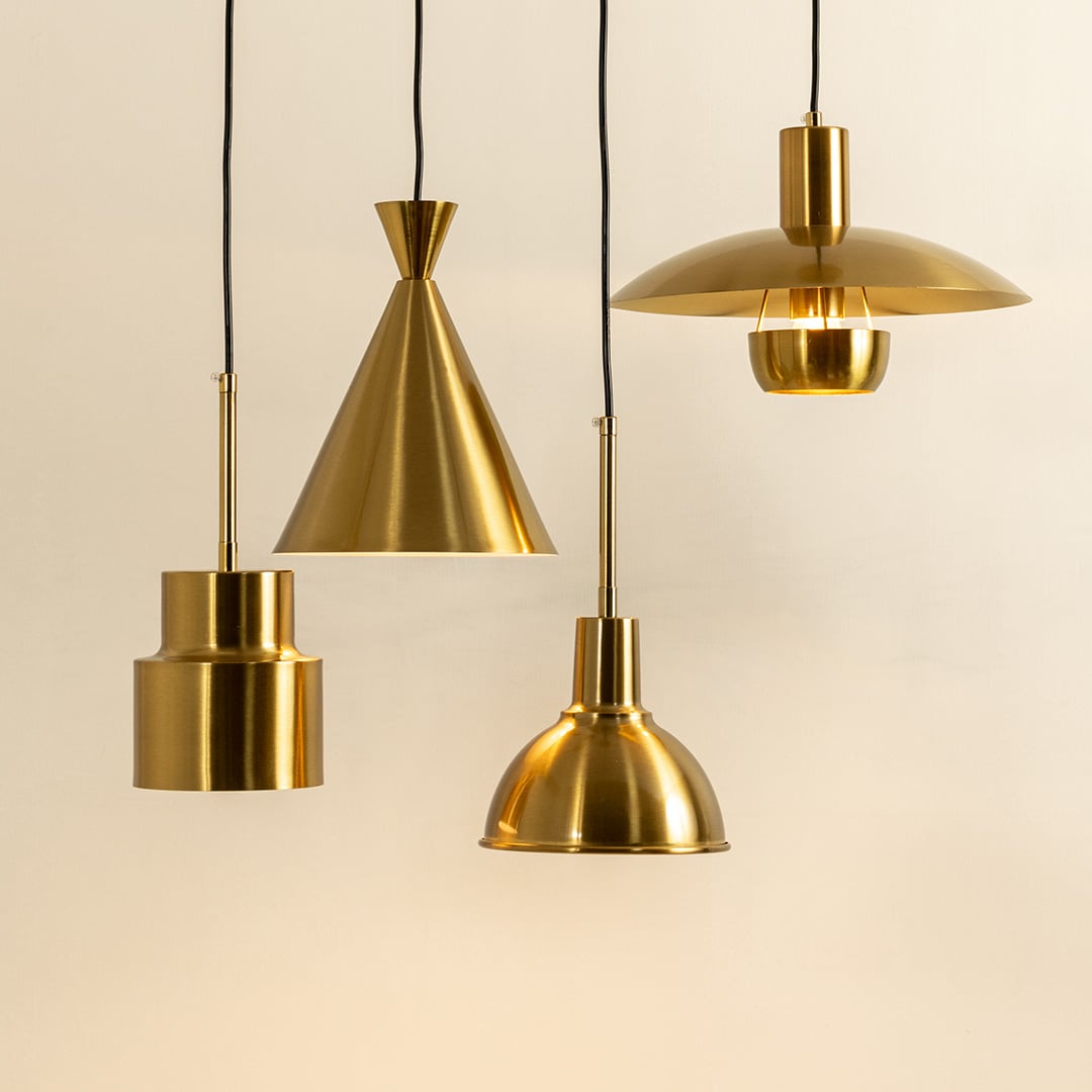 A modern set of metal pendant lights glowing warmly against a soft beige background each suspended at varied heights creating elegant contemporary interior décor.