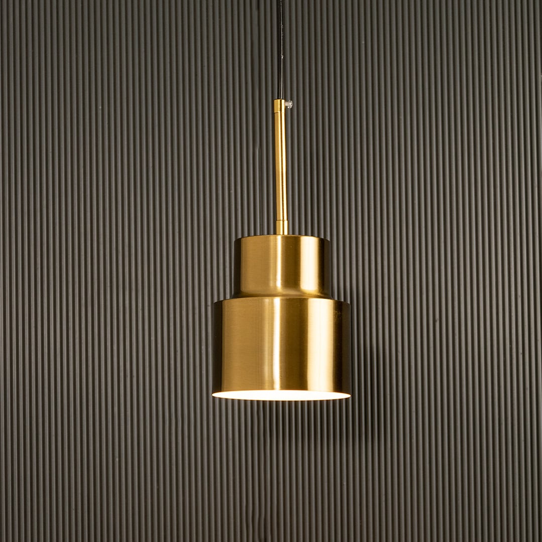 A tiered metal pendant light glowing gently before a ribbed dark background adding sculptural warm lighting and artistic contemporary décor.