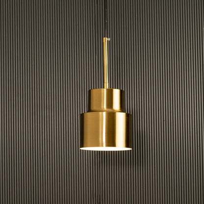 A tiered metal pendant light glowing gently before a ribbed dark background adding sculptural warm lighting and artistic contemporary décor.