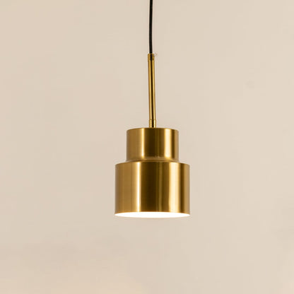 A tiered metal pendant light shining gently against a smooth beige background adding sculptural warm lighting and sophisticated contemporary décor.