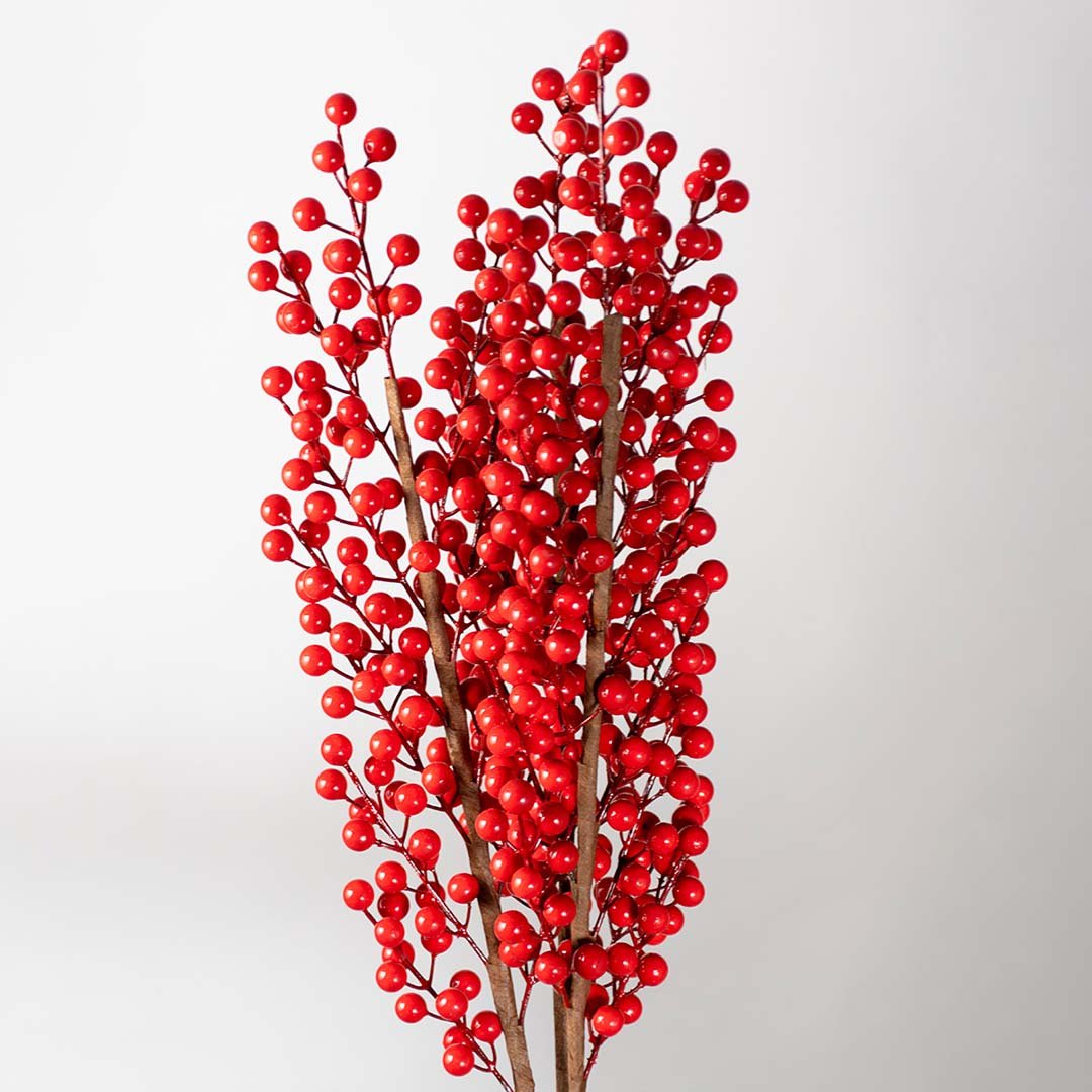 Lush closeup of vibrant red artificial winter berry branch stems for festive holiday centerpiece table decoration.