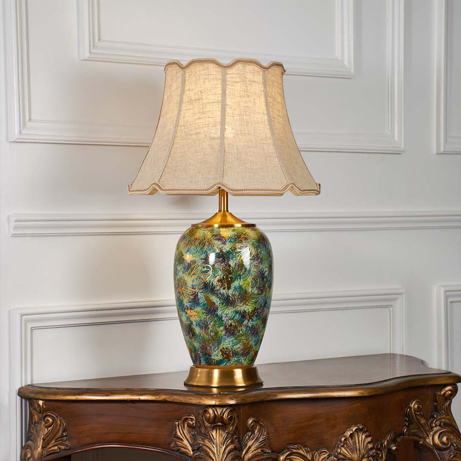 Multicolor floral ceramic table lamp with scalloped fabric shade creating luxurious traditional ambient lighting on a console table.
