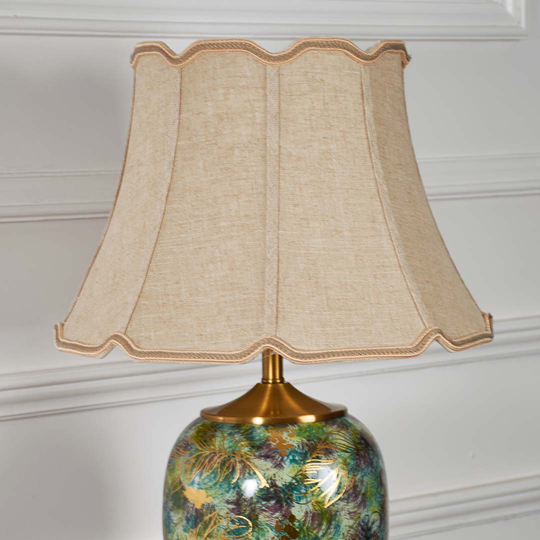 Closeup of ceramic table lamp with light off capturing the green artistic pattern gold accents and smooth glossy finish for refined decor.