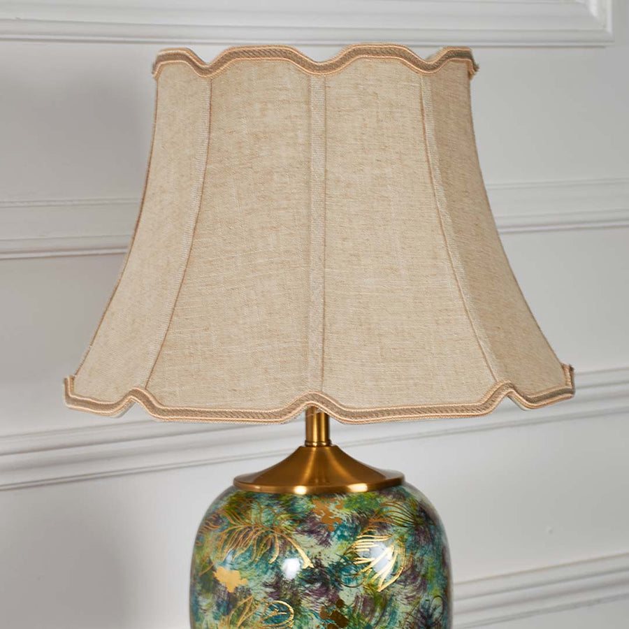 Closeup of ceramic table lamp with light off capturing the green artistic pattern gold accents and smooth glossy finish for refined decor.