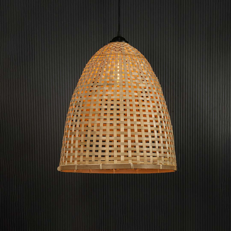 Woven bamboo pendant light glowing on black background with tall dome wicker shade for bohemian home lighting.