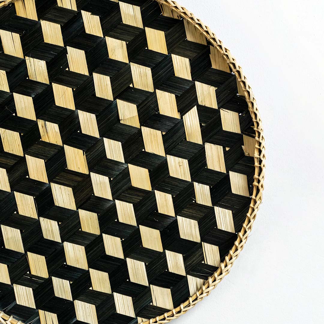 Closeup of handwoven bamboo basket showing intricate black and natural checkered weave pattern and artisan craftsmanship.