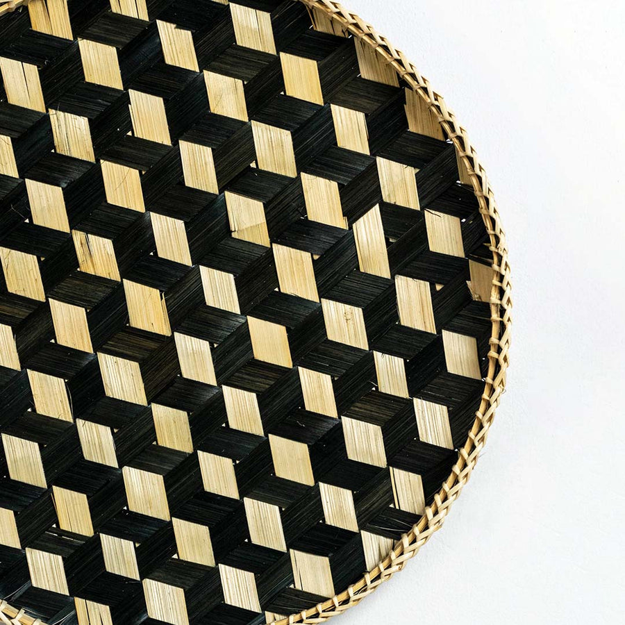 Closeup of handwoven bamboo basket showing intricate black and natural checkered weave pattern and artisan craftsmanship.