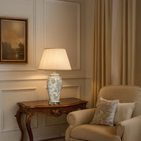 Elegant ceramic table lamp with floral detailing placed on a carved wooden console in a warm classic living room creating a soft ambient glow.