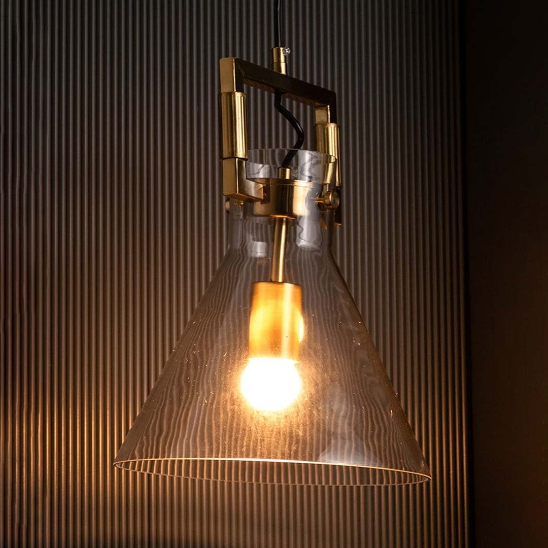 Glass cone pendant light displayed with light on against a black backdrop enhancing its warm illumination and polished gold finish.