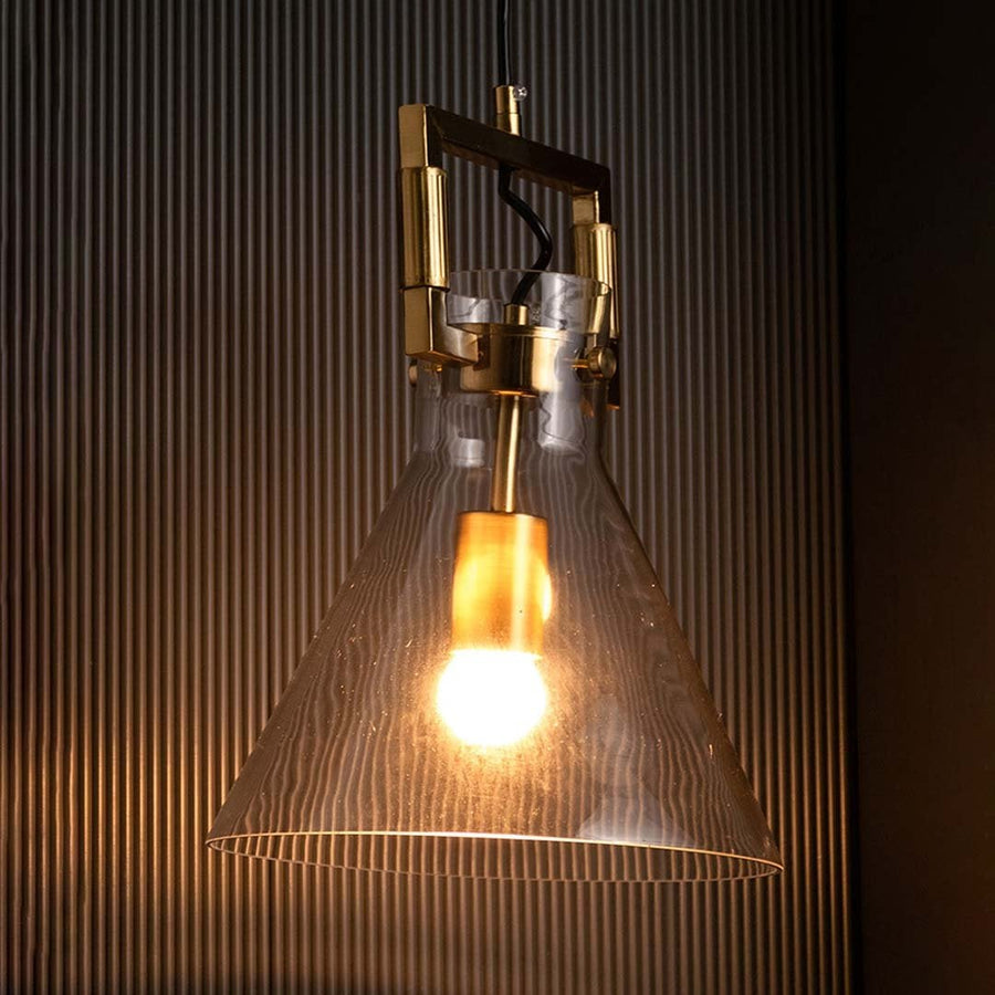 Glass cone pendant light displayed with light on against a black backdrop enhancing its warm illumination and polished gold finish.