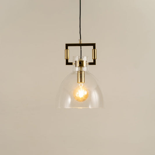 Clear dome glass pendant light with gold detailing shown with light on against a white background highlighting its warm glow and modern style.