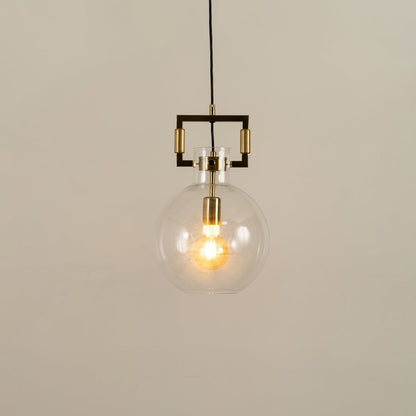 Clear glass globe pendant light with gold hardware shown with light on against a white background highlighting its warm glow and modern design.
