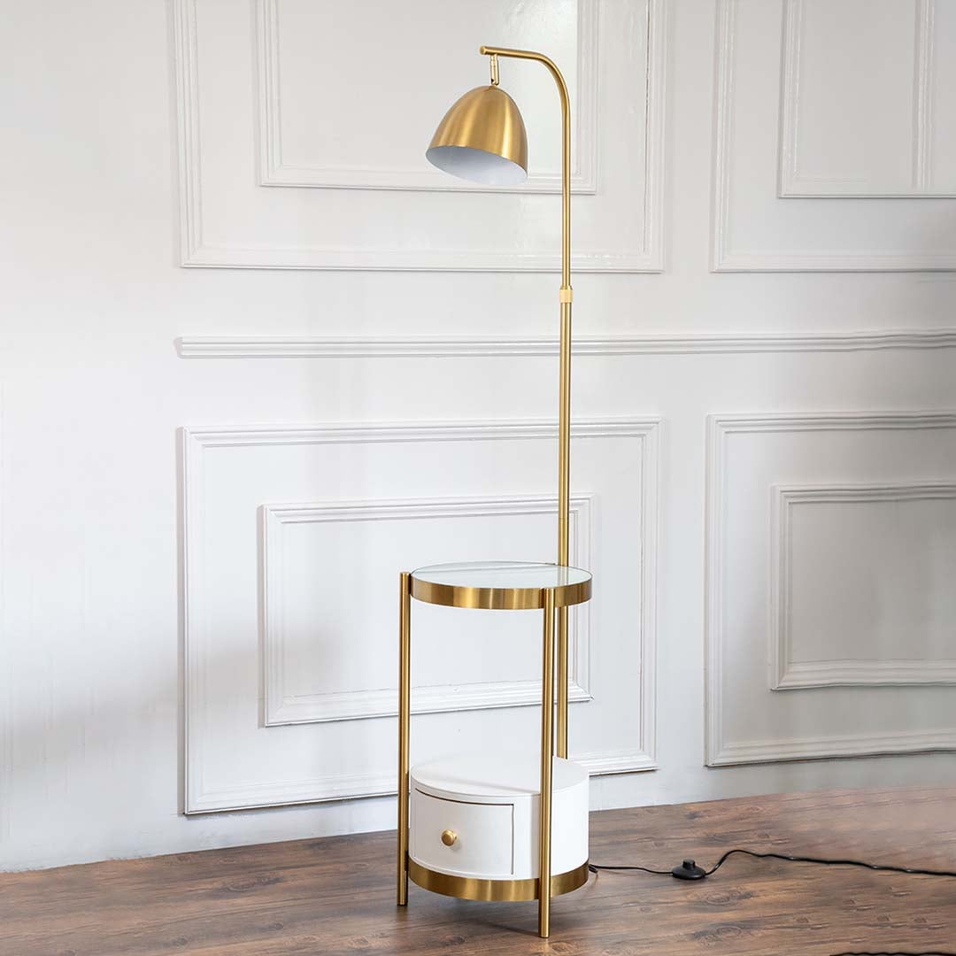 Gold floor lamp with round glass table and drawer turned off displayed on plain white background.